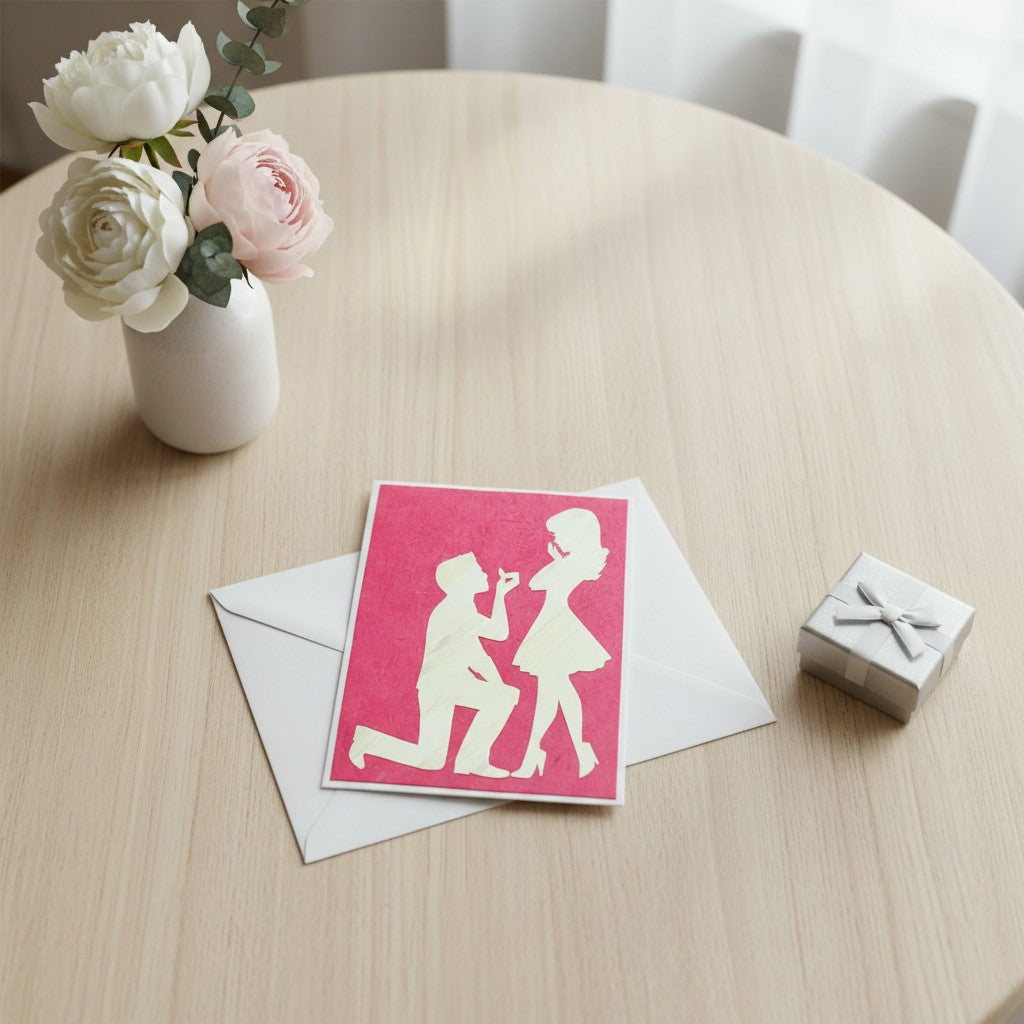 Lokta Cards hand-carved proposal card featuring a man on one knee offering a ring to a woman against a textured red background.