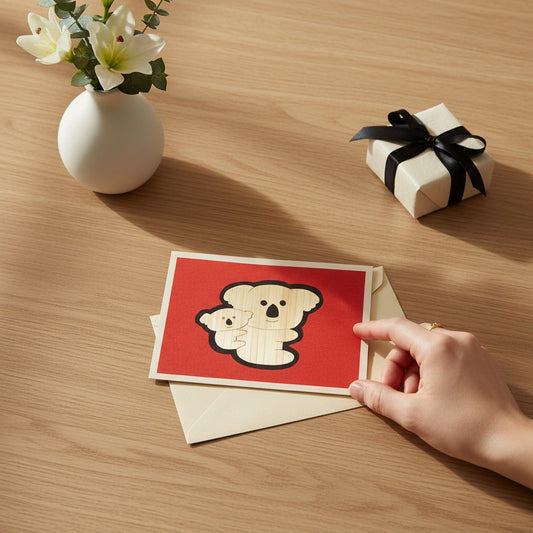 Lokta Cards hand-carved greeting card featuring a mother and baby koala on a red background.